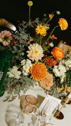 an arrangement of flowers and greenery on a table