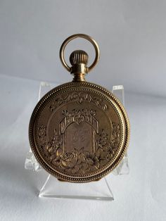 14 Kt solid gold Elgin hunt case pocket watch from 1884. This mechanical hand winding watch is lever set which means the lever on the front must be pulled out in order to set the hands on this style watch. The mechanical movement is in good working condition. The fancy case features a scenic house with floral designs all the way around the back cover The front cover also has fancy floral designs it has initials engraved in the center the engraving is very fancy and hard to decipher I think it is Victorian Engraved Gold Watches, Antique Gold Round Pocket Watch, Antique Gold Pocket Watch With Locket For Formal Occasions, Antique Finish Gold Pocket Watch, Formal Antique Gold Pocket Watch With Locket, Gold Round Pocket Watch With Antique Finish, Antique Gold Locket Pocket Watch For Formal Occasions, Antique Engraved Pocket Watch For Wedding, Antique Round Pocket Watch For Anniversary