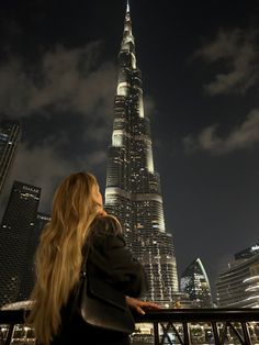 a woman looking at the city lights and skyscrapers