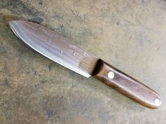 a knife that is on top of a table with a wooden handle and blade sticking out of it