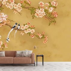 two birds sitting on a branch with flowers painted on the wall behind it in a living room