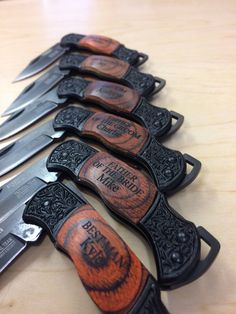 five knives are lined up next to each other on a wooden table with engraved labels