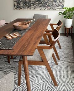 a dining room table and chairs in front of a large art piece on the wall