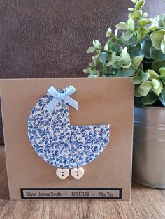 a blue and white card with a baby's pramk on it next to a potted plant