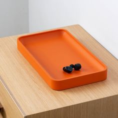 an orange tray sitting on top of a wooden table next to earbud plugs