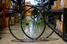 two bicycle wheels with green spokes on the floor in a storage room next to boxes