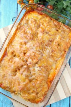 a casserole dish with meat and cheese in it sitting on a wooden cutting board