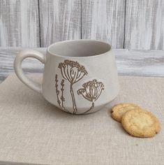 two cookies sitting on top of a table next to a coffee cup with flowers painted on it