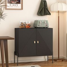 a black cabinet sitting next to a lamp on top of a hard wood floor