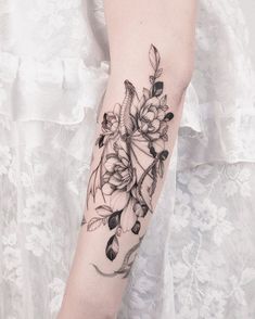 a woman's arm with flowers and leaves on it