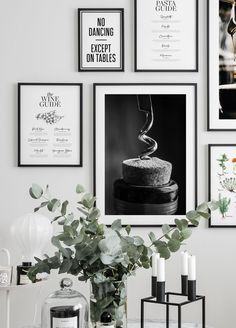 black and white photographs hang on the wall above a table with candles, vases and flowers