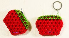 two red and green beaded fruit shaped keychains on a white tablecloth