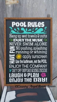 a pool rules sign sitting on top of a wooden chair in front of a building