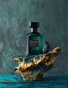 a bottle of perfume sitting on top of a piece of driftwood next to a rock