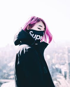 a woman with pink hair wearing a black hoodie that says sup on it