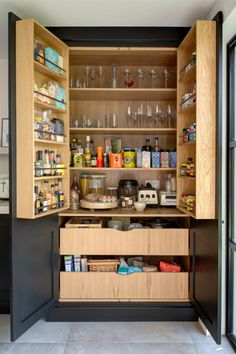 an open cabinet in the kitchen with wine glasses and other items on it's shelves