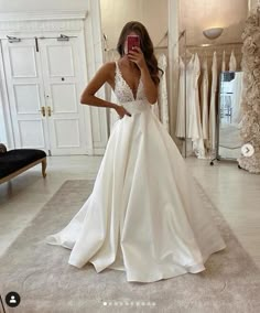 a woman taking a selfie in her wedding dress while looking at her cell phone