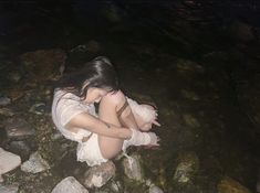 a woman sitting on rocks in the water