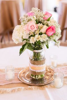 a vase filled with white and pink flowers on top of a table next to candles