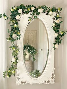 a mirror with flowers and greenery around it