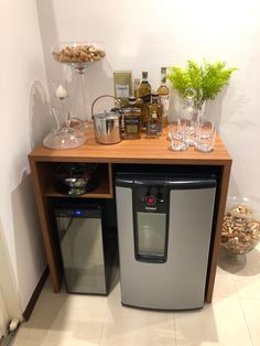 a small bar with wine glasses and bottles on the top, next to an ice chest