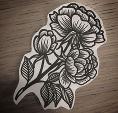 a sticker with flowers on it sitting on top of a wooden table next to a phone