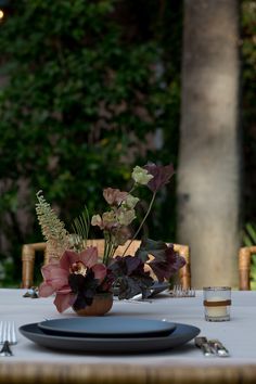 the table is set with plates, silverware and flowers