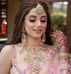 a woman in a pink and gold outfit with jewelry on her head, looking at the camera