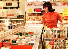 a woman is pushing a shopping cart in a grocery store