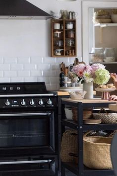 a kitchen with an oven, stove and table in front of the counter top is filled with flowers