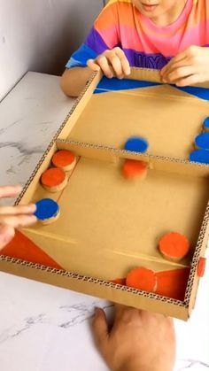 a young boy is playing with an orange and blue board game