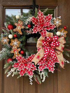 a christmas wreath with gingerbreads, holly and snowflakes hanging on a door