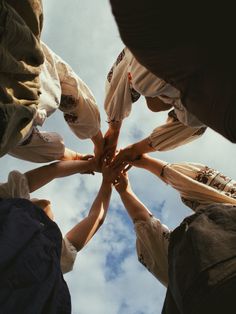 a group of people standing in a circle with their hands on top of each other