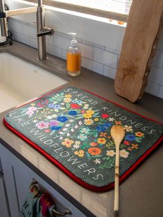 a wooden spoon sitting on top of a kitchen counter next to a flowered mat