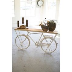 a bicycle is sitting in front of a table with plants on it and a clock