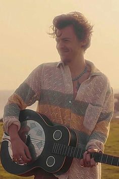 a man holding an acoustic guitar in his hands