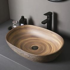 a wooden bowl sink sitting on top of a counter next to a faucet