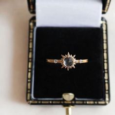 an engagement ring in a black velvet box with gold trimmings and diamond accents