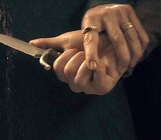 a person holding a knife in their hand with both hands on the other side of the knife