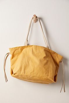 Easy and relaxed, this chic tote bag is featured in a slouchy style and canvas fabrication, with leather details for an edgy touch. **Features:** Tote style, slouchy design, canvas fabrication, leather tie sides, top handles, cinched closure, interior zip pocket **Why We | Daybreaker Tote Bag by FP Collection at Free People in Yellow Cotton Hobo Bag With Adjustable Strap For Shopping, Canvas Shoulder Tote Bag With Rolled Handles, Summer Leather Hobo Bag, Canvas Tote Shoulder Bag With Rolled Handles, Modern Canvas Bag With Leather Handles For Summer, Modern Canvas Bags With Rolled Handles, Chic Canvas Weekender Bag With Leather Handles, Summer Leather Hobo Bag For Everyday, Summer Everyday Leather Hobo Bag