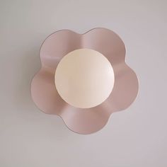 a round light fixture mounted on the side of a wall with a flower shaped design