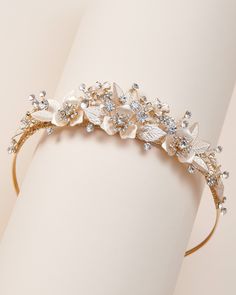 a gold headband with white flowers and leaves on the side, sitting on a table