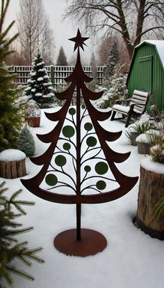 a metal christmas tree sitting on top of a snow covered ground next to a wooden bench