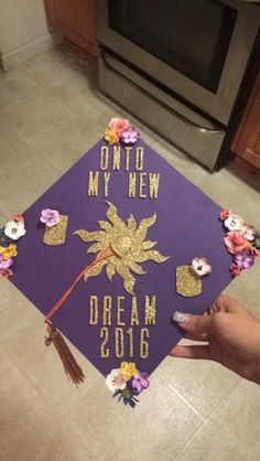 a purple and gold graduation cap with flowers on the front that says, onto my new dream 2016