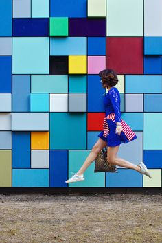 a woman is running in front of a colorful wall