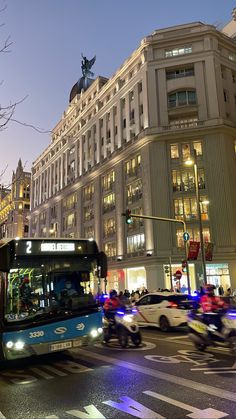 a city bus driving down a street next to tall buildings and traffic lights at night