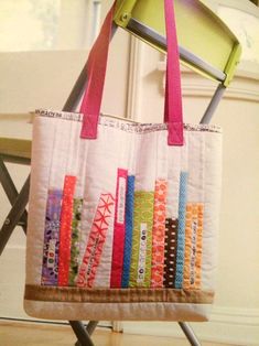 a multicolored tote bag sitting on top of a folding chair next to a window