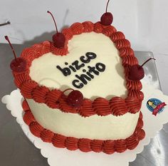 a heart shaped cake with the words pizza chito written on it and cherries