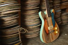 a small wooden guitar sitting on top of a floor next to stacks of books and papers