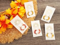 three pairs of earrings sitting on top of a wooden table next to some yellow flowers